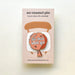 Peach-and-orange whoopee cushion enamel pin reading let that shit go on a chair-illustrated backing card.